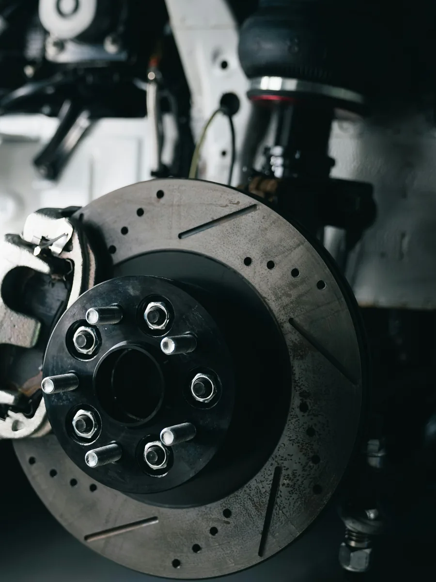 Drilled and slotted brake disc on a bare hub, suspension exposed